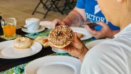a person holding a donut in front of a table at Le Saline Rooms Marzamemi in Marzamemi