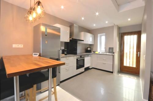 a kitchen with white cabinets and a wooden table at Appartement proche Walibi in Les Avenières