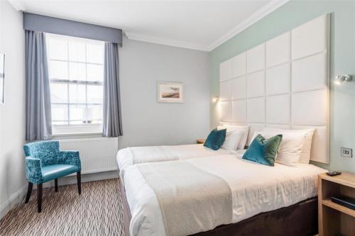 a hotel room with a bed and a blue chair at Kingscliff, BW Signature Collection in Clacton-on-Sea