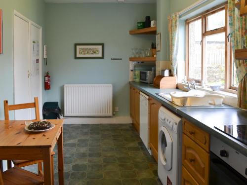 a kitchen with a sink and a washing machine at Paddock Cottage in Alnwick