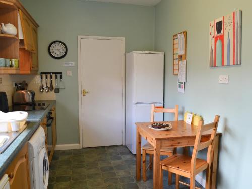 a kitchen with a wooden table and a refrigerator at Paddock Cottage in Alnwick