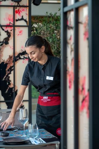 a woman standing at a table preparing wine glasses at Royal & Imperial Belvedere Resort in Hersonissos
