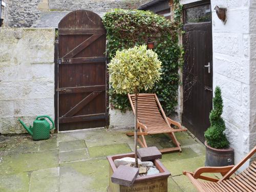a patio with a wooden gate and chairs and a door at Starry Cottage in Bakewell