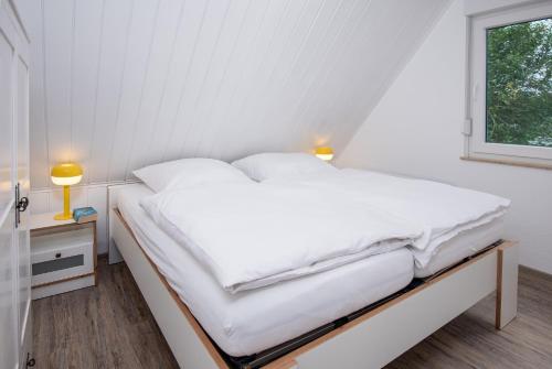a white bed in a room with a window at Seewind in Krummhörn