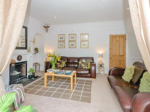 a living room with leather furniture and a fireplace at Number 1 Admiralty Cottages in Alverstoke