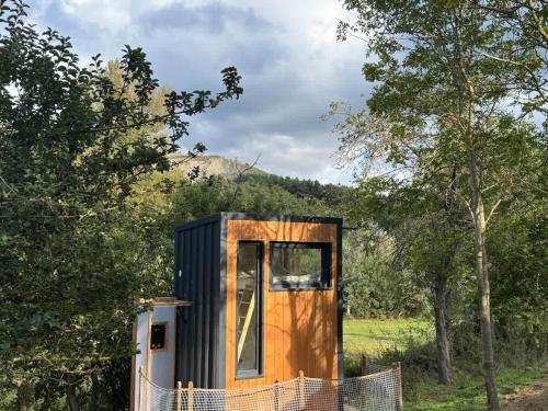 a small black and orange tiny house in a field at La Clairière de Peylenc - Refuge en Velay in Saint-Pierre-Eynac