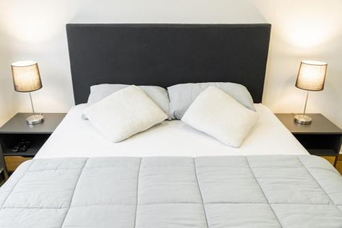 a bedroom with a white bed with two lamps at Departamento de lujo en zona Carmelitas in Asuncion