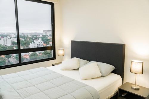 a bedroom with a white bed with a large window at Departamento de lujo en zona Carmelitas in Asuncion