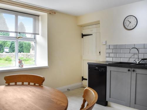 a kitchen with a table and a clock on the wall at The Old Cottage in Coanwood