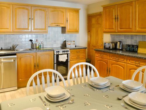 a kitchen with wooden cabinets and a table and chairs at East Lewiston in Drumnadrochit