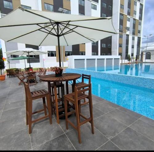 a table and chairs with an umbrella next to a pool at Staycation Houz,Sepanggar in Kota Kinabalu