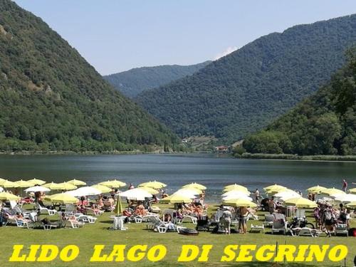 a group of people sitting under umbrellas near a lake at LUKAS HOME CON IL CUORE Appartamento 3 camere al piano terra e appartamento 1 camera in taverna in Merone