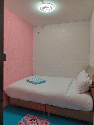 a bedroom with a bed with a pink wall at D​ Luck​ Hostel in Kanchanaburi