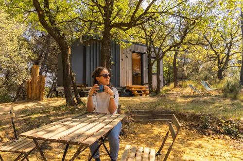 a woman sitting on a picnic table taking a picture at Lodge Grand Confort en Nature - Salle de bain italienne - 10 min A7 in Mondragon