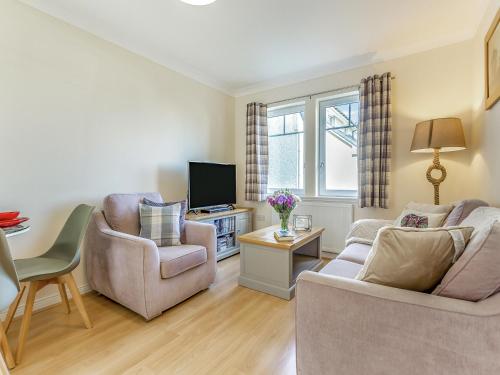 a living room with two chairs and a tv at Kincraig Apartment in Inshes