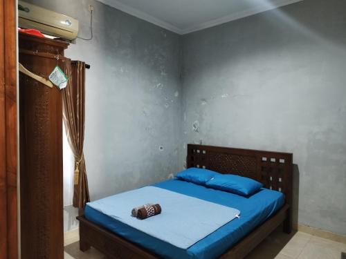 a bedroom with a bed with blue sheets and a bottle on it at Omah Semaki in Yogyakarta