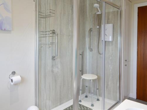 bagno con doccia in vetro e sgabello. di Mill Shore Cottage - 26817 a Pennan