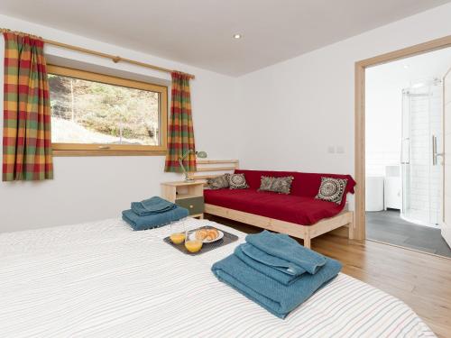 a living room with a red couch and some towels at Jill Strawbale House- Ukc2935 in Strontian