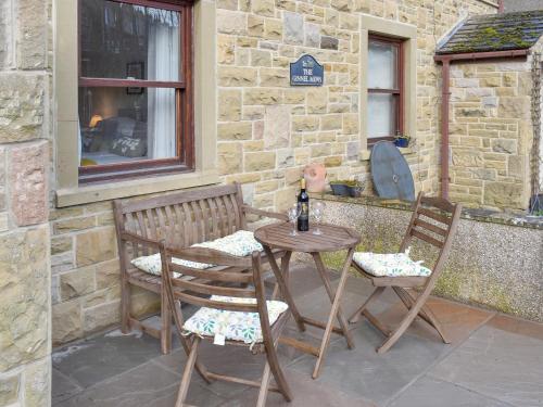 a table and two chairs sitting next to a building at The Ginnel Mews in Skipton