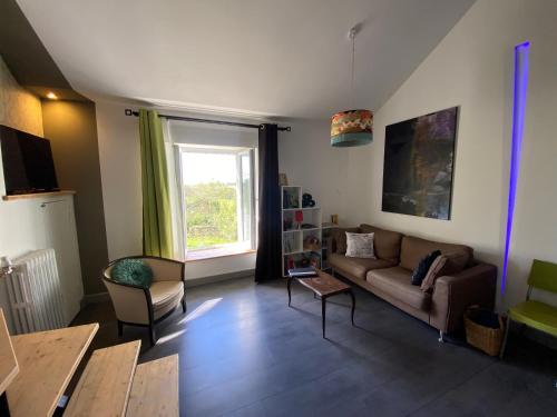 a living room with a couch and a window at L'Alcôve, maison d'artistes in Sacquenay