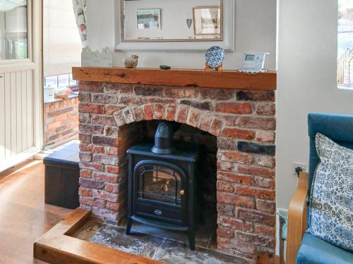 a brick fireplace with a stove in a living room at Ikkle Cottage in Blidworth