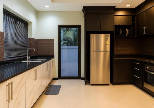 a kitchen with a stainless steel refrigerator and black cabinets at Luxury 5 Bedroom Funplace Pool Villa in Pattaya in Na Jomtien
