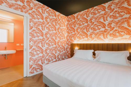 a bedroom with a bed with an orange wall at Collini Rooms, WorldHotels Crafted in Milan