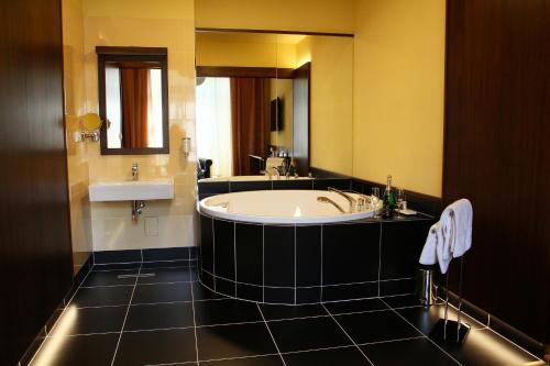 een grote badkamer met een bad en een wastafel bij Hotel Baltaci Starý Zámek in Napajedla