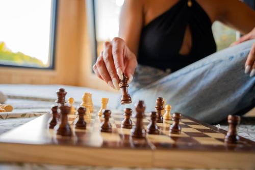 a woman playing chess on a wooden chessboard at Lodge en Nature - 30 min Saint-Emilion - Salle de bain à l'italienne in Mouliets-et-Villemartin