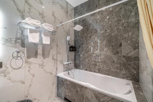 baño con bañera y ducha con paredes de mármol en Oasis Pandawa 6A - Sun, Sand and Serenity - 3BR Villa with Private Pool, en Ungasan
