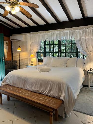 a bedroom with a large white bed with a wooden bench at Urikana Boutique Hotel in Teresópolis