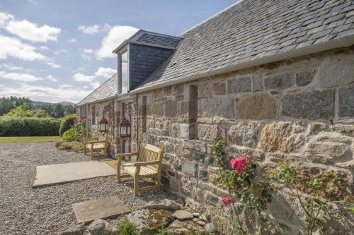a stone building with a bench in front of it at Drum Lodge in Nethy Bridge