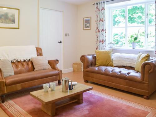 ein Wohnzimmer mit 2 Ledersofas und einem Couchtisch in der Unterkunft Wood Cottage in Cheriton