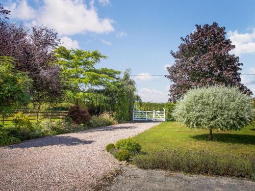 a gravel driveway with a white fence and a tree at Broadoak Barn in Ellesmere