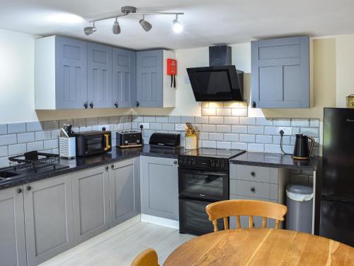 a kitchen with blue cabinets and a wooden table at The Old Cottage in Coanwood