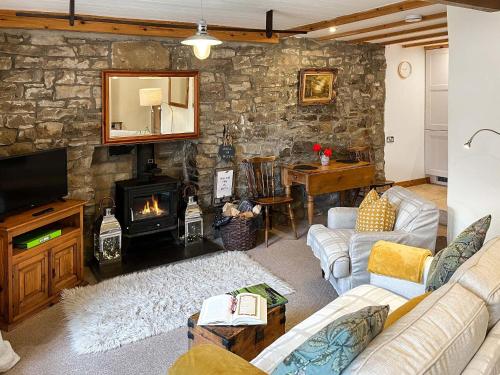 a living room with couches and a stone wall at Lock Heather Cottage in Reeth