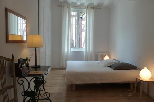 a bedroom with a white bed and two windows at Une Chambre Dans L'atelier De R in Rouen