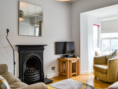 ein Wohnzimmer mit Kamin und Fernseher in der Unterkunft Fairfield Cottage in Ambleside