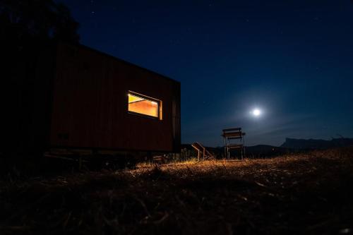 a barn with a window and a chair at night at Prairie de la Gervanne - Panorama Drôme & Vercors in Beaufort-sur-Gervanne