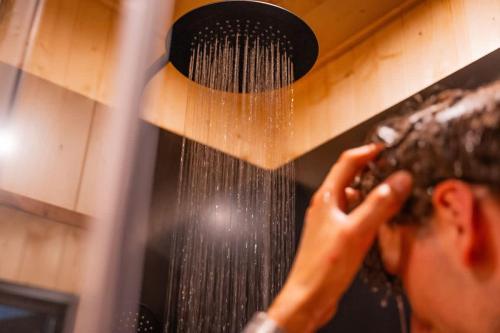 a man is washing his hair with a shower at Homnest - Observatoire des Préalpes & Cheval in Puy-Saint-Martin