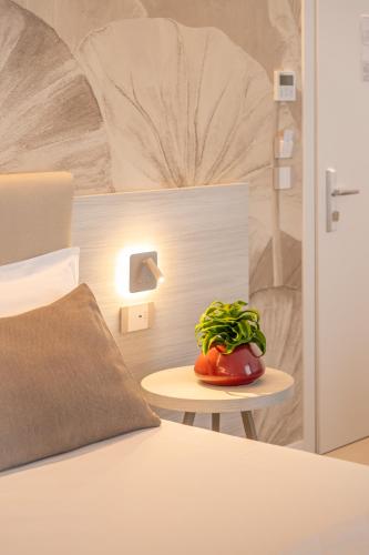 a plant sitting on a table next to a bed at Hotel Mirafiori in Lido di Jesolo