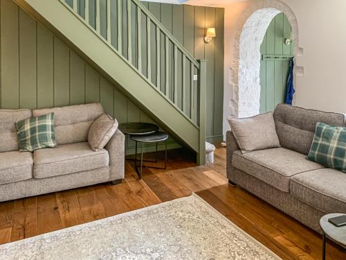a living room with two couches and a staircase at The Old School in Kettlewell