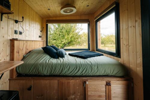 a bed in a tiny house with a window at Tiny-House à 1h20 de Lyon - Salle de bain italienne - Lit Grand confort in Bruailles