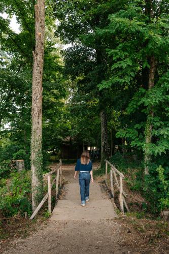 a woman walking down a path in the woods at Tiny-House à 1h20 de Lyon - Salle de bain italienne - Lit Grand confort in Bruailles
