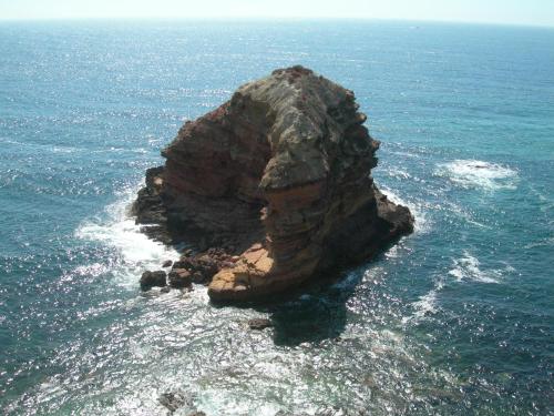 a rock formation in the ocean with the water at Carrapateiramar Guest House in Carrapateira
