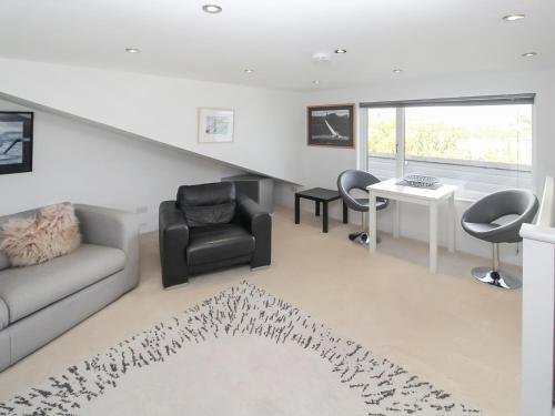 een woonkamer met een bank, stoelen en een tafel bij The Loft - Uk50517 in Falmouth