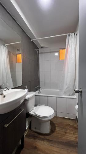 a bathroom with a toilet and a sink and a tub at Escapadas Elqui Departamento en La Serena in La Serena