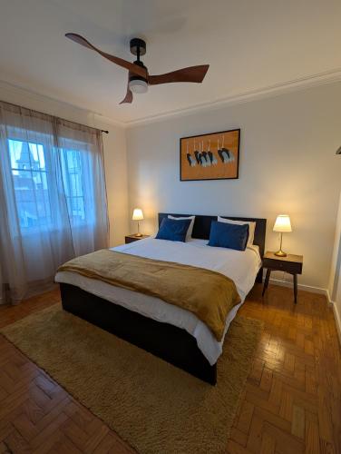 a bedroom with a large bed with a ceiling fan at Centro Coração in Tomar