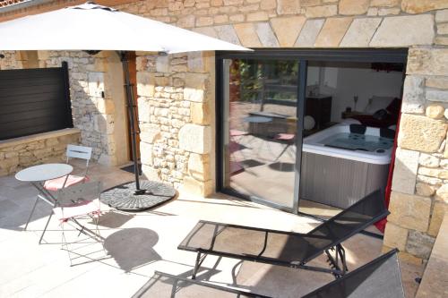 a patio with chairs and a table and an umbrella at Gites spa de charme L ETOILE SPA in Beynac-et-Cazenac