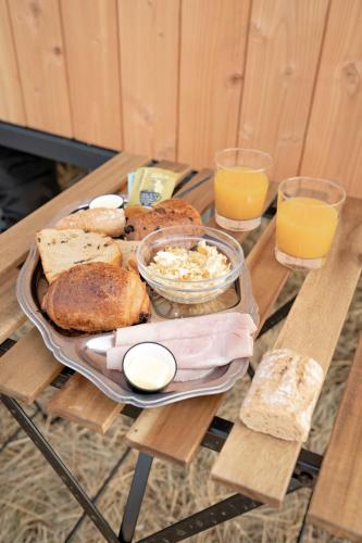 a table with a tray of bread and glasses of orange juice at Homnest - L'Indiana Ranch - 20 min de Vichy in Espinasse-Vozelle